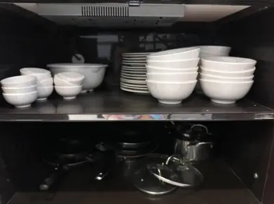 a shelf with white bowls and plates and a tea kettle at Private 4BR Model Home center Patong in Patong Beach