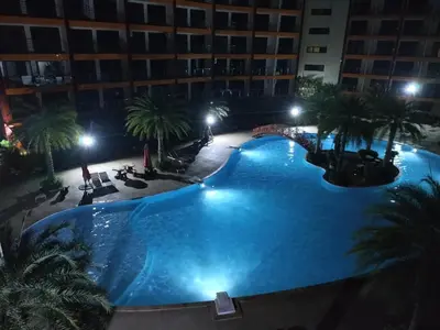 a large swimming pool with palm trees and a building at Heavenly place 777 on Mai Khao in Ban Mai Salae