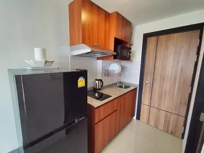 a kitchen with a black refrigerator and wooden cabinets at Heavenly place 777 on Mai Khao in Ban Mai Salae