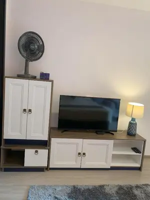 a living room with a tv and a fan on a cabinet at The Base Central Phuket in Phuket Town