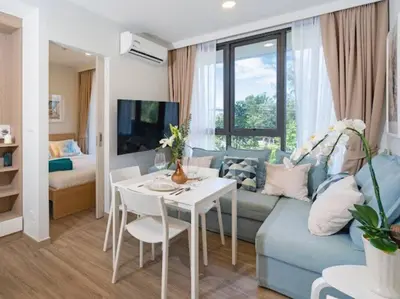 a living room with a blue couch and a table at Bangtao , Laguna , 5 minutes from the bench, 2 bedroom in Ban Thalat Choeng Thale