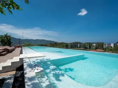 a large swimming pool with a view of a city at Bangtao , Laguna , 5 minutes from the bench, 2 bedroom in Ban Thalat Choeng Thale