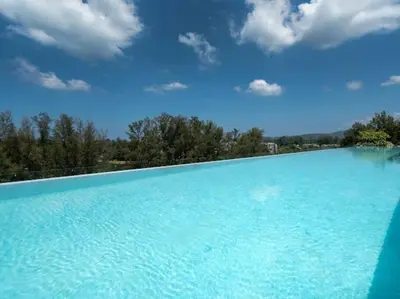 a large pool of blue water with trees in the background at Bangtao , Laguna , 5 minutes from the bench, 2 bedroom in Ban Thalat Choeng Thale