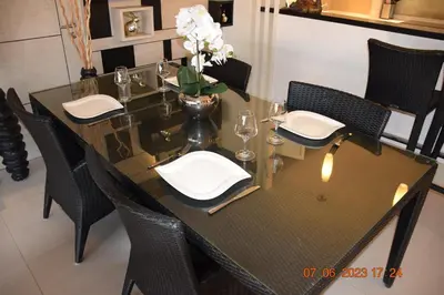 a dining table with chairs and a vase with flowers on it at KALIM RESIDENCE UNIT 133 VUE MER in Patong Beach