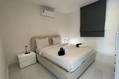 a bedroom with a white bed with a black bag on it at Karon Butterfly Condominium Brandnew 68m2 apartment, seaview, pool access, 500m to beach in Karon Beach