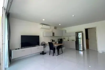 a large white kitchen with a table and a television at Karon Butterfly Condominium Brandnew 68m2 apartment, seaview, pool access, 500m to beach in Karon Beach