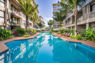 a swimming pool in the middle of a building with palm trees at Pool Access Condo Bangtao Beach in Bang Tao Beach
