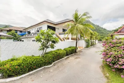 a house with a white fence and palm trees and flowers at Chonlada Pool Villa - 6-BR - Kamala Beach in Phuket Town