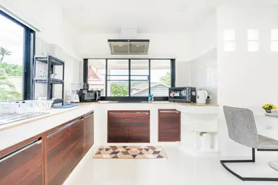a kitchen with wooden cabinets and a counter top at Chonlada Pool Villa - 6-BR - Kamala Beach in Phuket Town