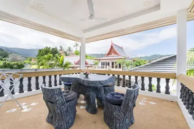 a dining room with a table and chairs on a balcony at Chonlada Pool Villa - 6-BR - Kamala Beach in Phuket Town