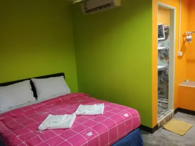 a green room with a bed with towels on it at Rc Guest House in Phi Phi Don