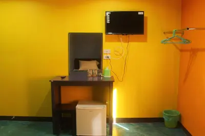 a room with a desk and a tv on a yellow wall at Rc Guest House in Phi Phi Don