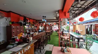 a restaurant with tables and chairs and a bar at Vech Guesthouse Patong in Patong Beach