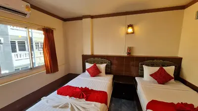 two beds in a room with red and white pillows at Vech Guesthouse Patong in Patong Beach