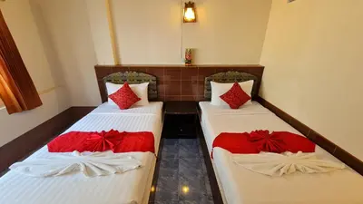 two beds in a room with red pillows on them at Vech Guesthouse Patong in Patong Beach