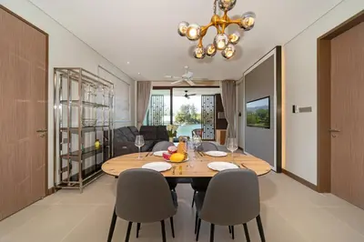 a dining room and living room with a table and chairs at Laguna Angsana Apartments Lake View in Bang Tao Beach