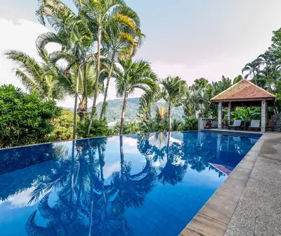 a pool at a resort with palm trees and a gazebo at Baiyok Villa seaview and edge pool in Patong Beach