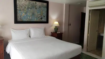 a bedroom with a white bed and a painting on the wall at Rendez Vous Hotel in Patong Beach