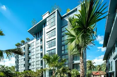 a tall building with palm trees in front of it at Tropics Kamala Deluxe Pool View Apartment CTG P402 in Kamala Beach