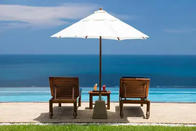 two chairs and a table with an umbrella on the beach at Villa Aye in Kamala Beach