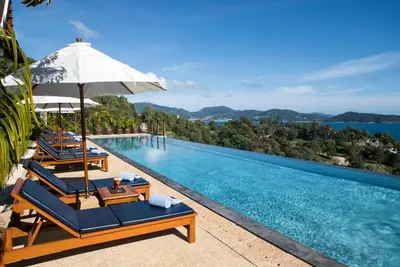 a swimming pool with lounge chairs and an umbrella at Villa Aye in Kamala Beach