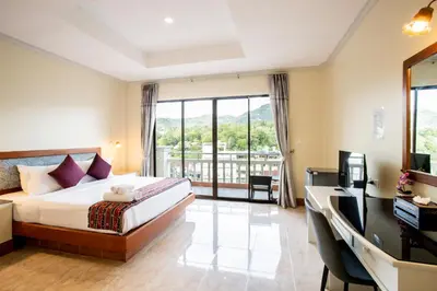 a bedroom with a bed and a desk with a television at Tri's Miracle Kata Beach Side in Kata Beach
