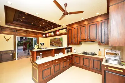 a kitchen with wooden cabinets and a ceiling fan at Unique&Nice 7BD pool villa in heart Nanai Patong in Patong Beach