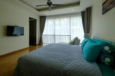 a bedroom with a bed with blue pillows and a television at 3bdr Townhouse In Laguna Park #116 in Bang Tao Beach