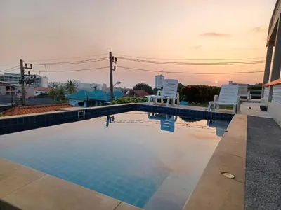 a swimming pool with two lawn chairs and the sunset at Scan House Apartment in Karon Beach