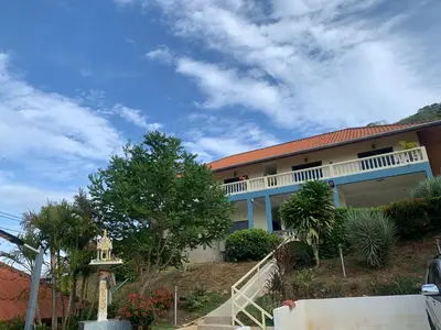 a house on a hill with stairs and trees at Scan House Apartment in Karon Beach