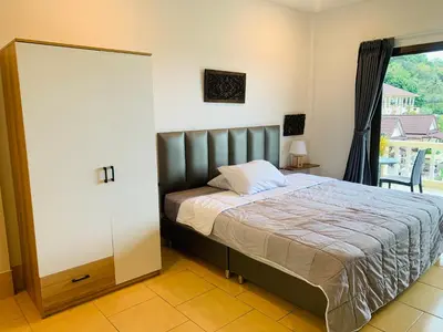 a bedroom with a bed and a large window at Scan House Apartment in Karon Beach
