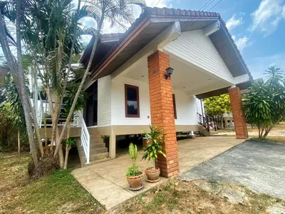 a white house with palm trees in front of it at Peaceful 2BR Garden Retreat Bangtao Beach A2 in Ban Thalat Choeng Thale