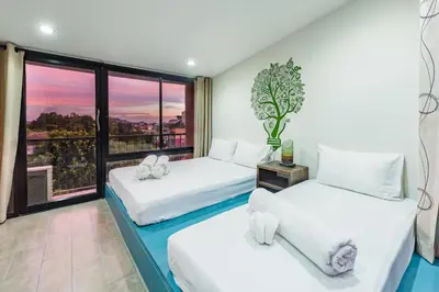 two beds in a room with a window at Eco Hostel in Phuket Town