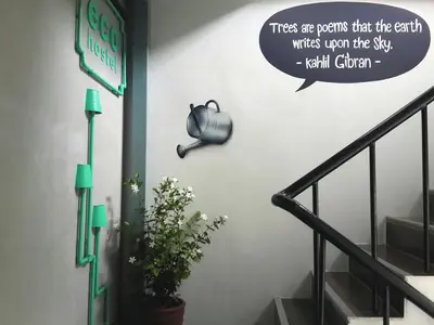 a wall with a sign that reads trees are poems that the earth writes upon at Eco Hostel in Phuket Town