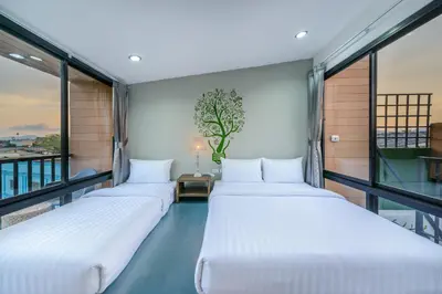 a row of beds in a room with windows at Eco Hostel in Phuket Town