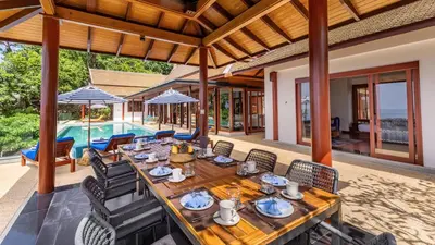 an outdoor dining area with a table and chairs and a pool at Villa Varya in Amphoe Thalang