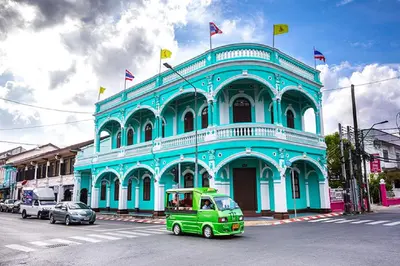 a green car parked in front of a blue building at xx GO INN Phuket Old Town ภูเก็ตโอลทาวน์ ย่านเมืองเก่า in Phuket Town