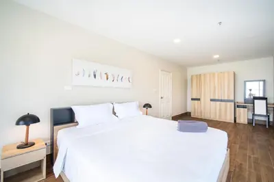 a bedroom with a large white bed and a table at Patong tower Superior Seaview 4BR-2102 in Patong Beach