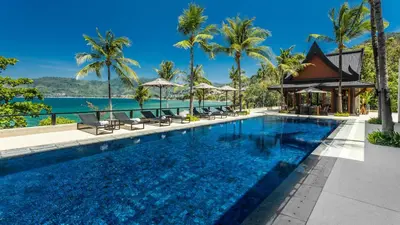 a swimming pool at a resort with palm trees at Villa Purissara in Phuket Town
