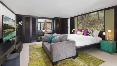 a bedroom with a bed and a couch and a tv at Villa Purissara in Phuket Town