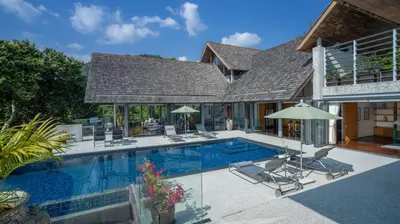 a swimming pool with chairs and a house at Villa Lomchoy in Phuket Town