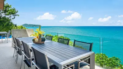 a blue table and chairs on a balcony overlooking the ocean at Villa Lomchoy in Phuket Town