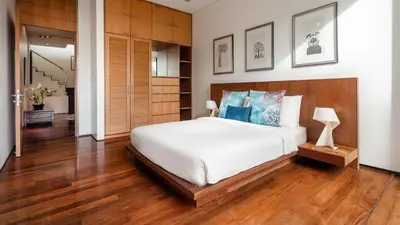 a bedroom with a large white bed and wooden floors at Villa Lomchoy in Phuket Town