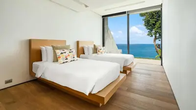 two beds in a room with a view of the ocean at Villa Saengootsa in Phuket Town