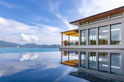a house with a reflection in the water at Villa Fah Sai in Phuket Town