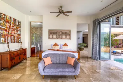 a bedroom with a bed and a chair at Villa Fah Sai in Phuket Town