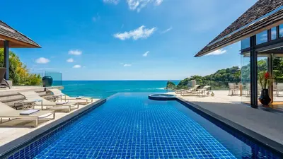 a swimming pool with chairs and a view of the ocean at Villa Viman in Kathu