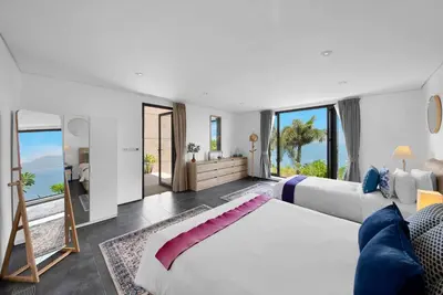 a bedroom with a large bed and large windows at Villa Rom Trai in Kathu