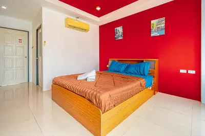 a bedroom with a red wall and a bed at Nice to meat you Rooms in Patong Beach