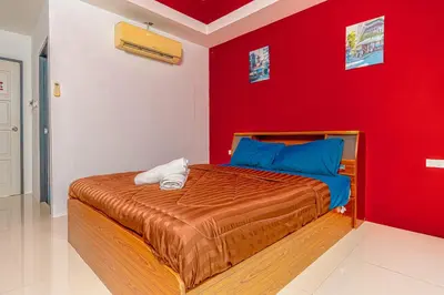 a bedroom with a red wall and a bed at Nice to meat you Rooms in Patong Beach